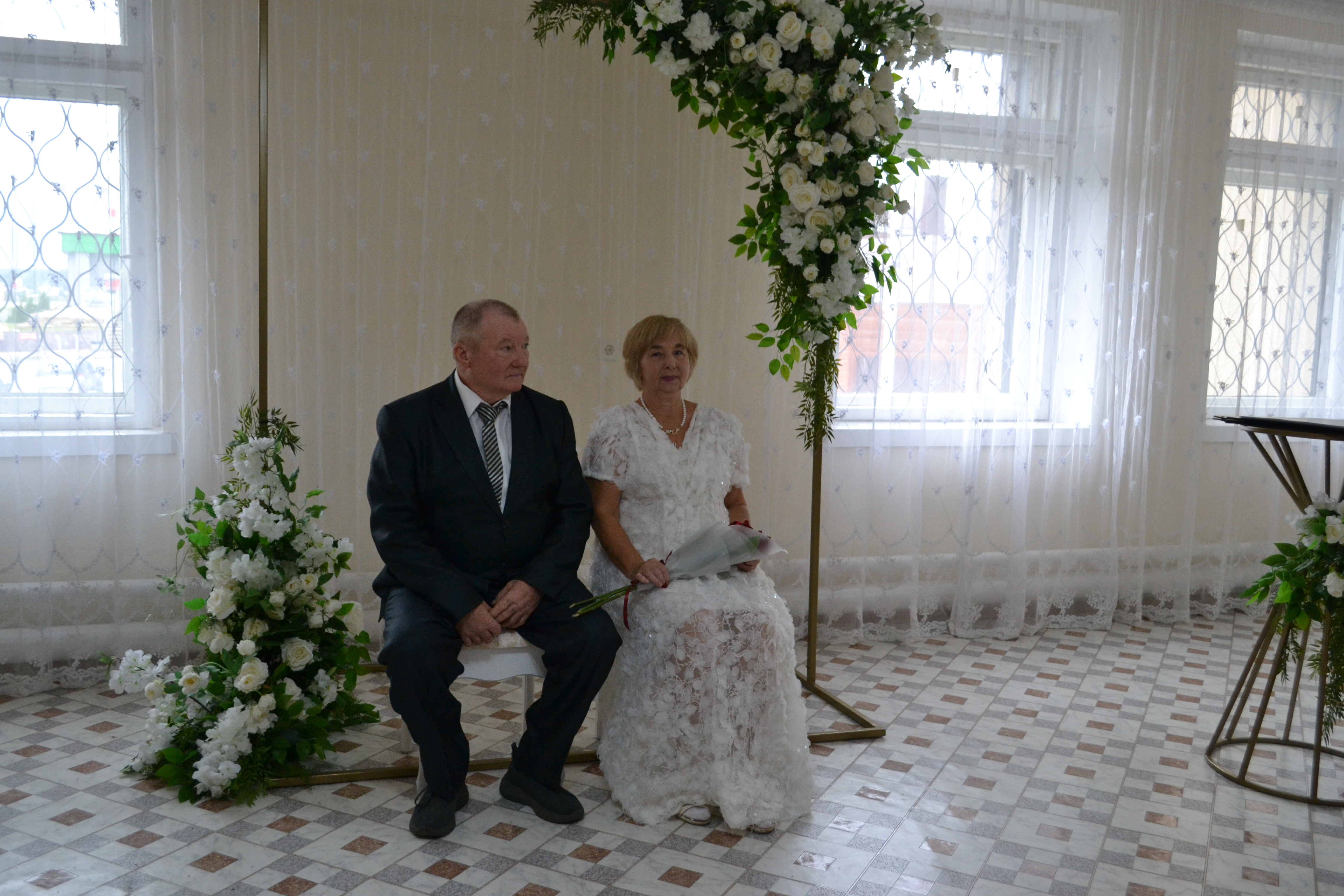 Ирина Ивановна Свиридова в изящном белом платье, а рядом с ней «жених» Владимир Николаевич Свиридов в строгом костюме