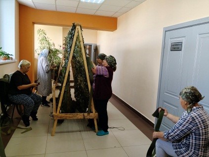  Женщины вручную вплетают ленты в ячейки, стараясь избегать чётких геометрических линий